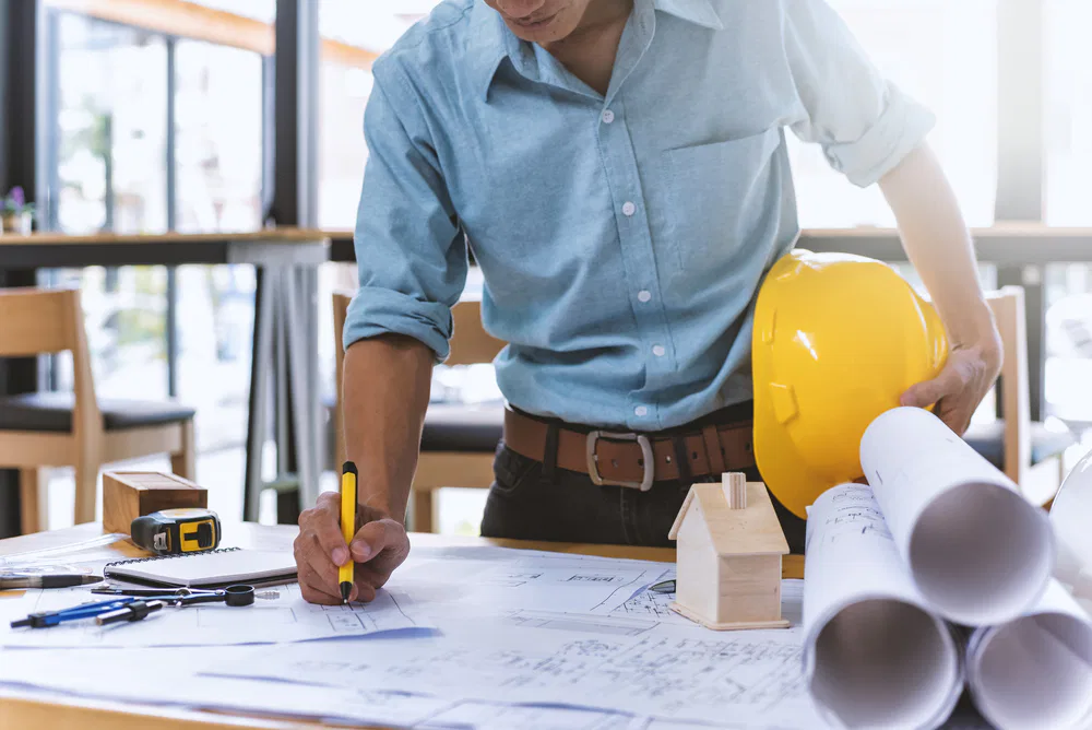 A man wearing a hard hat and glasses works on a project labeled 'Crown Finish' at a construction site.