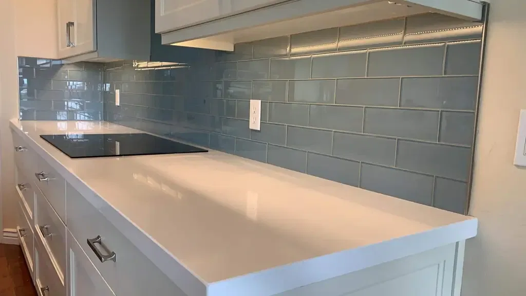 Modern kitchen with glossy blue subway tile backsplash and white quartz countertop.
