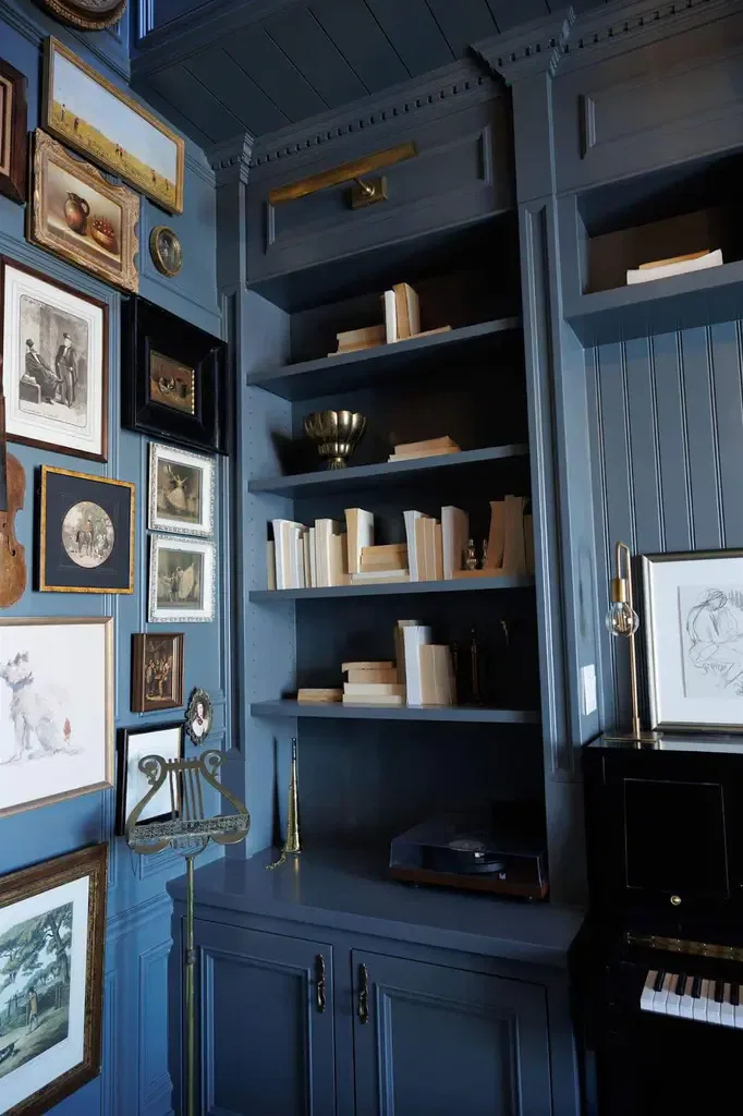 A blue room featuring a piano and bookshelves filled with books