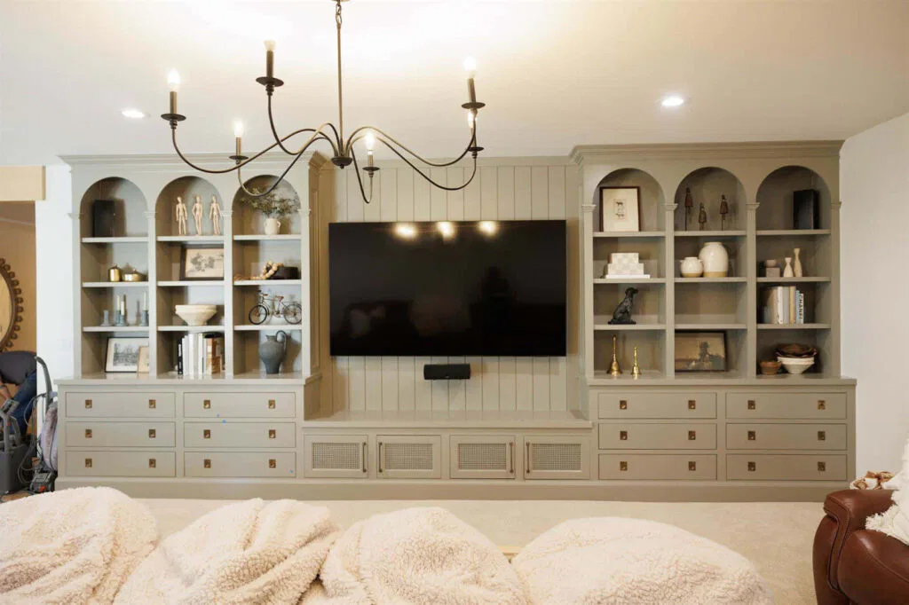 A spacious living room featuring a large TV and custom bookcases with books and decor